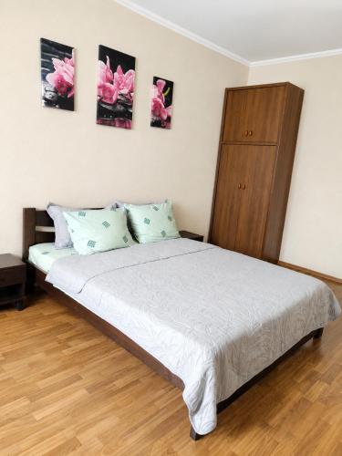 a bedroom with a white bed with a wooden cabinet at Apartment Ekaterina in Chornomorsk
