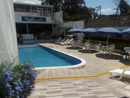 a swimming pool with tables and chairs and umbrellas at Blue Star Hotel in Melgar