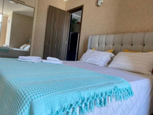 a bed with blue and white sheets and a mirror at Sea Towers 2 room apartment in Batumi