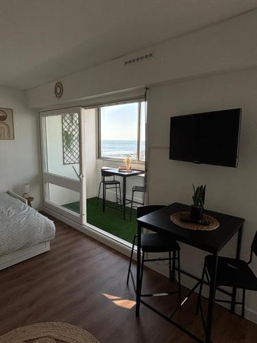 a living room with a bed and a table and a television at Saint Hilaire sea view accommodation in Saint-Hilaire-de-Riez