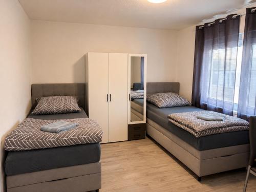 a room with two beds and a cabinet with a mirror at Worms City Suites Löwengasse in Worms