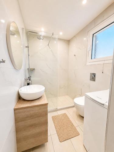 a white bathroom with a sink and a shower at Alexandra Apartment in Ipsos