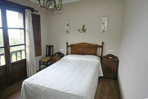 a bedroom with a white bed and a window at Casa de Aldea Los Valles in La Llera