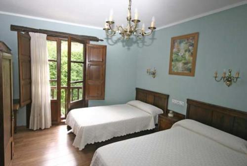 a bedroom with two beds and a chandelier at Casa de Aldea Los Valles in La Llera