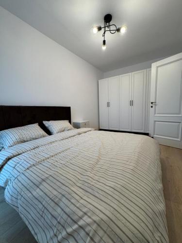 ein Schlafzimmer mit einem großen Bett und einer gestreiften Bettdecke in der Unterkunft Avenue in Arad