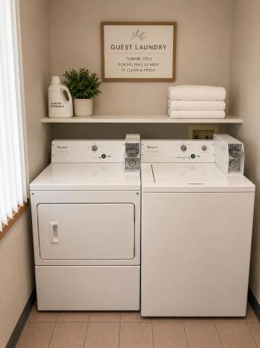 two white appliances sitting next to a shelf with towels at Days Inn by Wyndham Hinckley in Hinckley