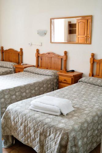 a room with three beds with a mirror and a mirror at Hostal Fuentesol in Madrid