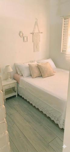 a bedroom with a white bed with a green floor at Casa das Plantas in Piraju