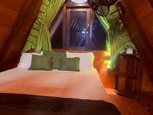 a bed with green and white pillows in a room at Rainforest Emerald Haven in Deniyaya