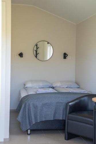 a bedroom with a bed with a mirror and a chair at Hvammur 6 with private hot tub in Hafnarhólmur