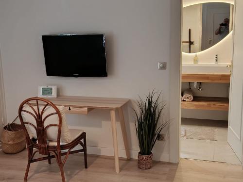 a television on a wall with a table and a chair at Très belle chambre à Metz in Metz