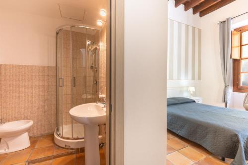 a bathroom with a sink and a toilet and a bed at Via Roma Rooms Guesthouse in Sassari