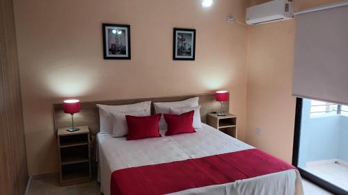 a bedroom with a bed with red pillows and two lamps at Apart Saavedra in Concordia