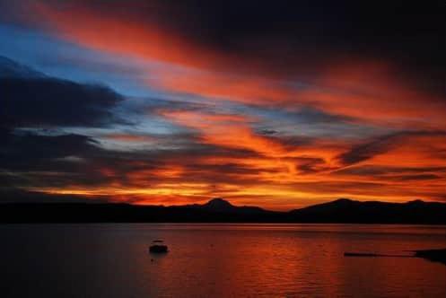 a sunset over a body of water with a boat at Luxury Cabin on Golf Course / Private Spa & Launch in Prattville
