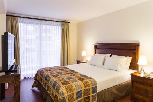 a hotel room with a bed and a television at Park Plaza Apartments in Santiago