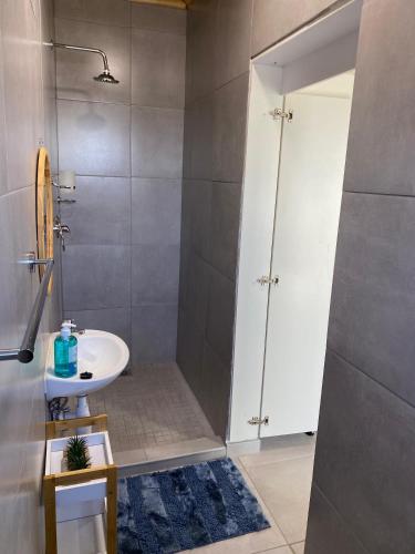 a bathroom with a white sink and a shower at Windy Dunes Self -Catering Accommodation, Luderitz in Lüderitz