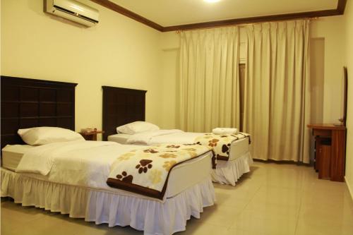 a hotel room with two beds and a window at The Apartments By Sedrah in Irbid
