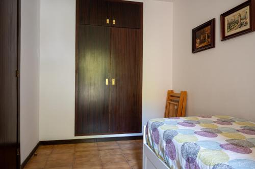 a bedroom with a bed and a wooden closet at AT121 Con piscina y cerca de la playa in Torredembarra