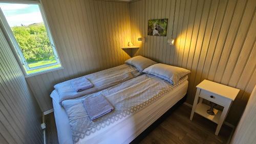 a small bed in a room with a window at Hvammur 1 with private hot tub in Drangsnes