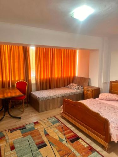 a bedroom with two beds and a table and a desk at Pensiunea Selena Bascov-Pitesti in Bascov