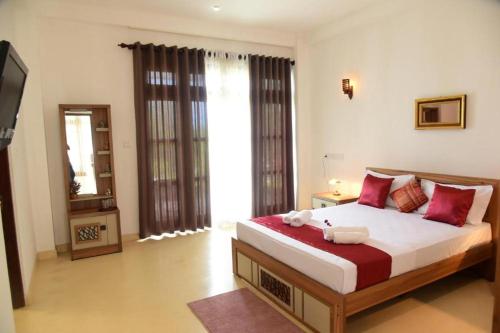 a bedroom with a large bed and a television at Ayurishi Villa in Hikkaduwa