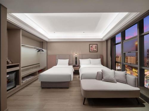 a hotel room with three beds and a tv at Mercure Luoyang Downtown in Luoyang