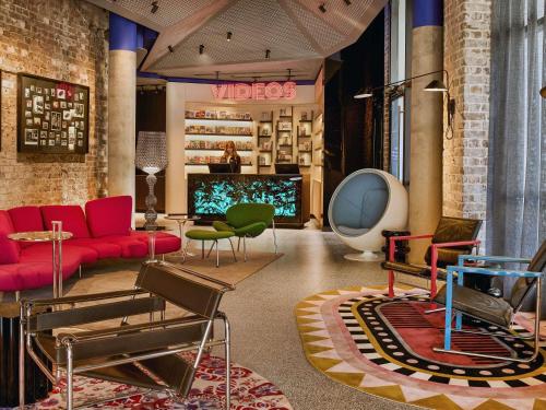 a lobby with a red couch and chairs and a tv at 25hours Hotel Sydney The Olympia in Sydney