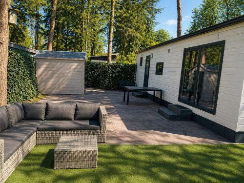 a backyard patio with a couch and a picnic table at Veluwe Droom Chalet in Hoenderloo