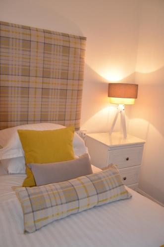 a bed with a yellow pillow and a night stand at Edinburgh37 in Edinburgh
