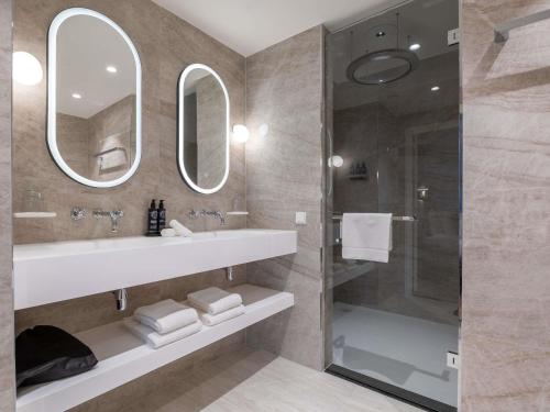 a bathroom with a sink and a shower with mirrors at Hotel Maison Maastricht Centrum - Handwritten Collection in Maastricht