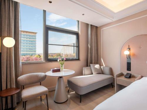 a hotel room with a bed and a table and a window at Mercure KunMing Airport in Kunming
