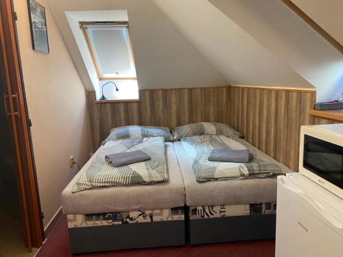 a small bed in a room with a window at Penzion Kolovna in Dobrá