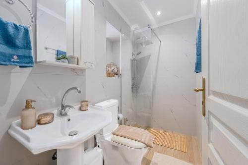 a white bathroom with a sink and a toilet at Olea holiday house in Astérion