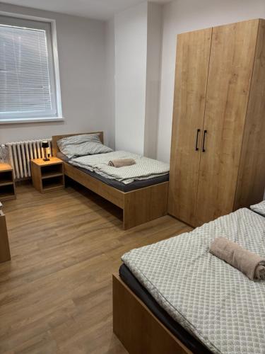 a bedroom with two beds and a wooden cabinet at Apartmán REBEKA in Holíč
