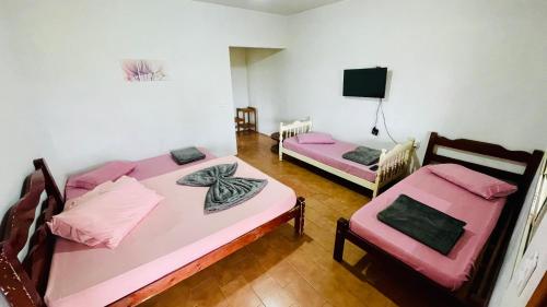 a room with two beds and a tv on the wall at Casa de campo in Botucatu