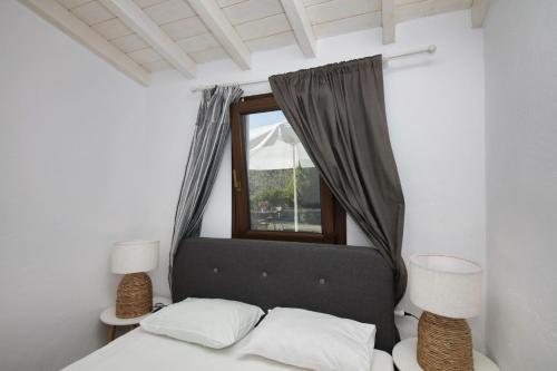a bedroom with a bed with a window and two lamps at VILLA VICTORIA in Ditropo