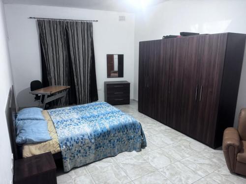 a bedroom with a bed and a cabinet and a desk at Quiet and Lovely Residence in St. Julianʼs