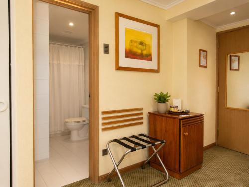 a bathroom with a toilet and a sink and a stool at LRH Viña del Mar and Convention Center - Ex Gala Hotel in Viña del Mar