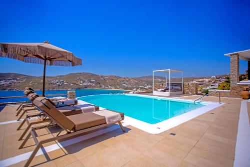 a villa with a swimming pool and an umbrella at South Star private Villa in Mikonos