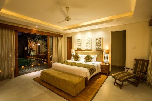 a bedroom with a bed and a chair and a window at Villa Seriska Dua Sanur with Private Pool in Sanur