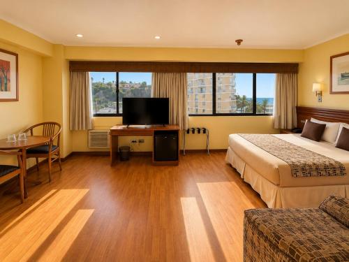 a hotel room with a bed and a television and a table at LRH Viña del Mar and Convention Center - Ex Gala Hotel in Viña del Mar