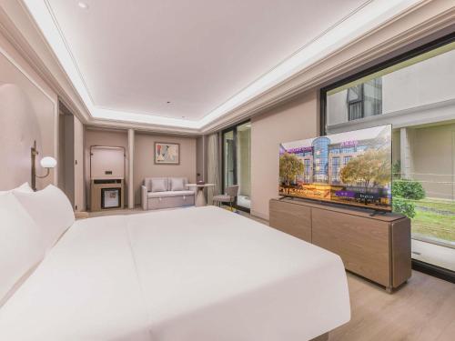 a bedroom with a large white bed and a flat screen tv at Mercure Beijing Future Science City in Beijing