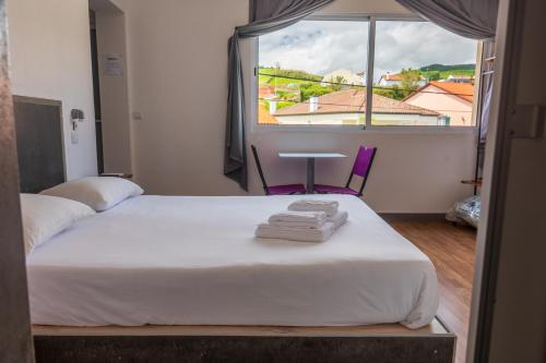 a room with a bed and a window with towels at GarçaView in Vila Franca do Campo