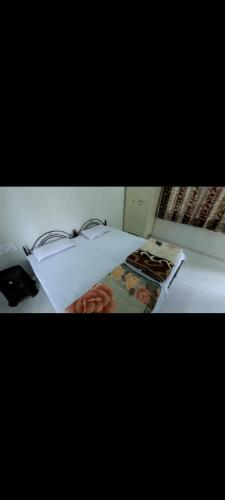 a bedroom with a white bed with flowers on it at krishna suraj villa in Chikalda