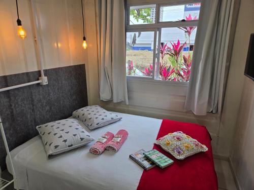 a bedroom with a bed with slippers and a window at Espaço Container Itapema - Loft I in Itapema