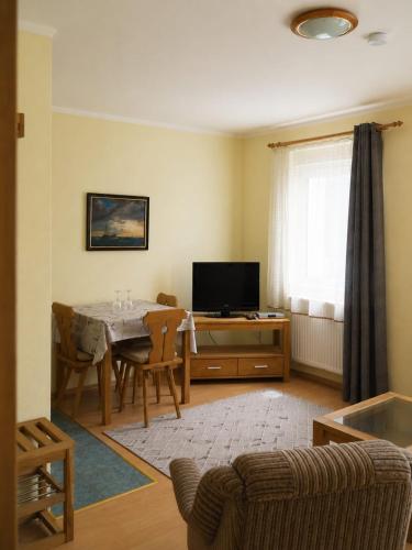 a living room with a table and a television at Pension NoAs in Sassnitz