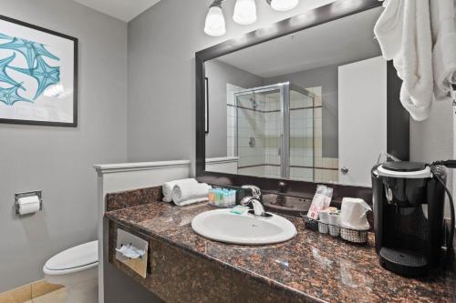 a bathroom with a sink and a toilet and a mirror at Sunset Haven Oceanfront Hotel in Depoe Bay