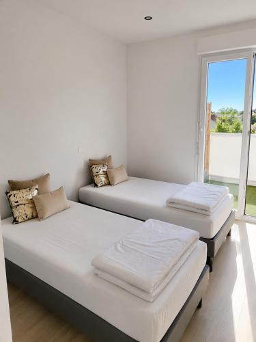 two beds in a room with a window at maison Labenne in Labenne