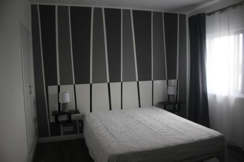 a bedroom with a bed and a striped wall at Casa do Tempo in Achada