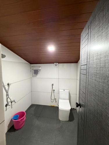a bathroom with a toilet and a red bucket at Koyiloth house by intertrip in Kalpetta